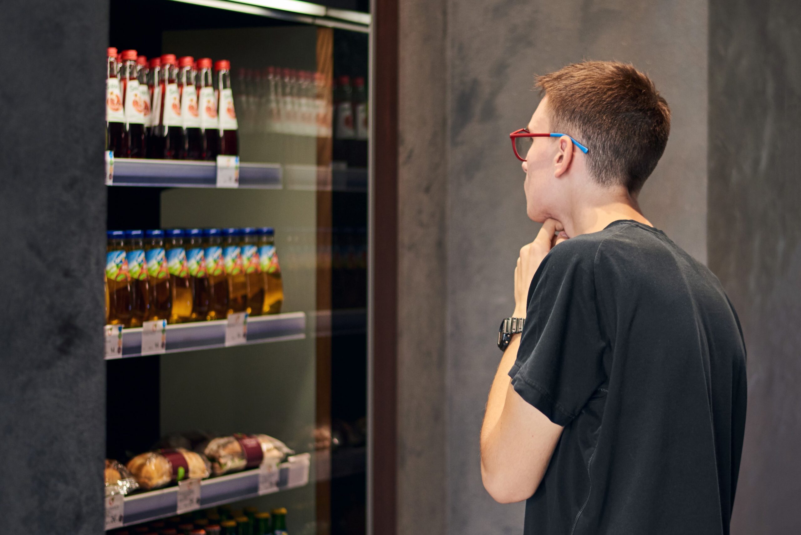 A man looking at the selection of drinks and food in a vending machine