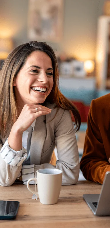 Cheerful business woman with a cup of coffee next to a phone and laptop