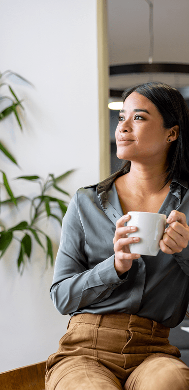 Thoughtful Latin American businesswoman taking a break and drinking a cup of coffee at the office