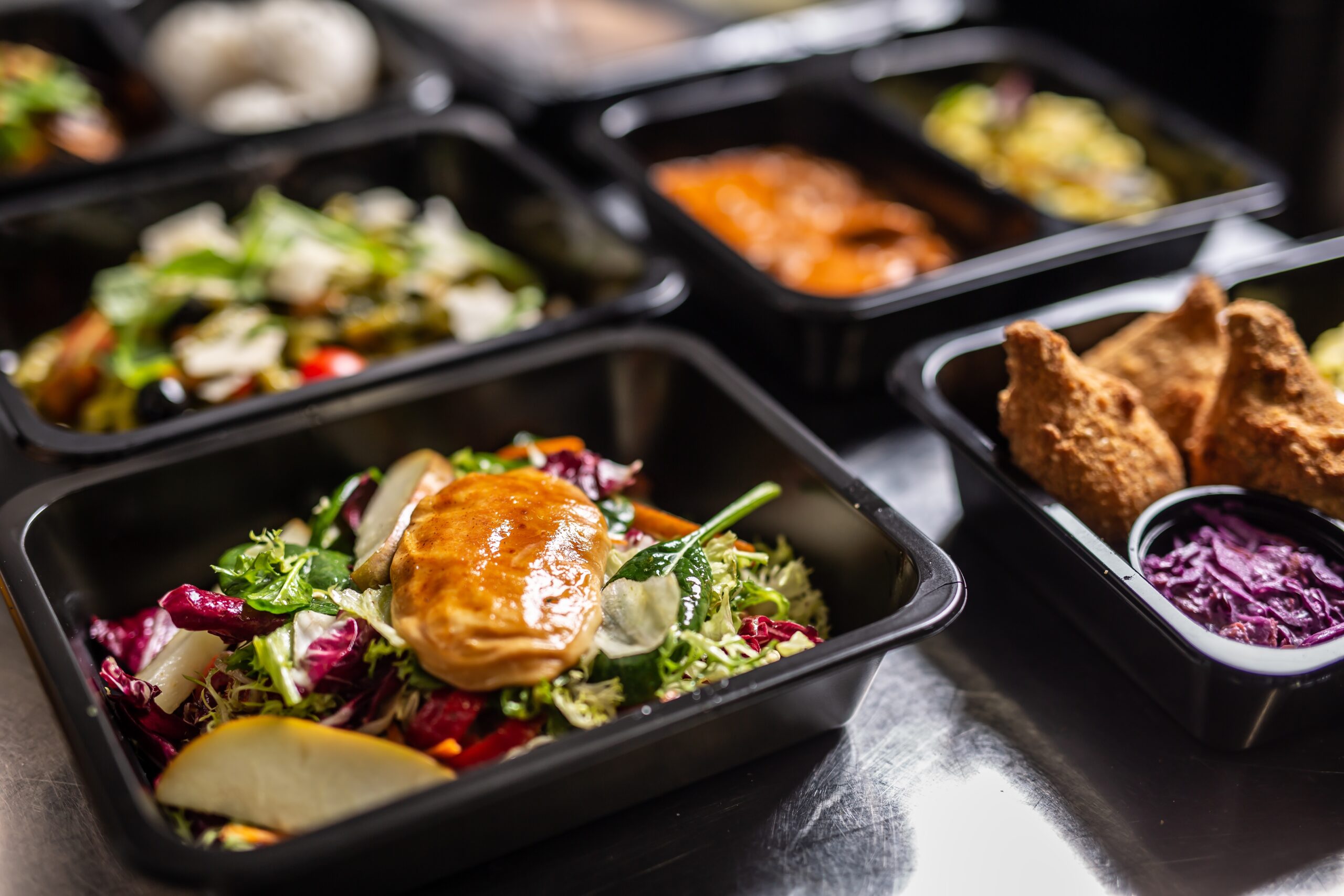 A selection of fresh meals with chicken over a salad