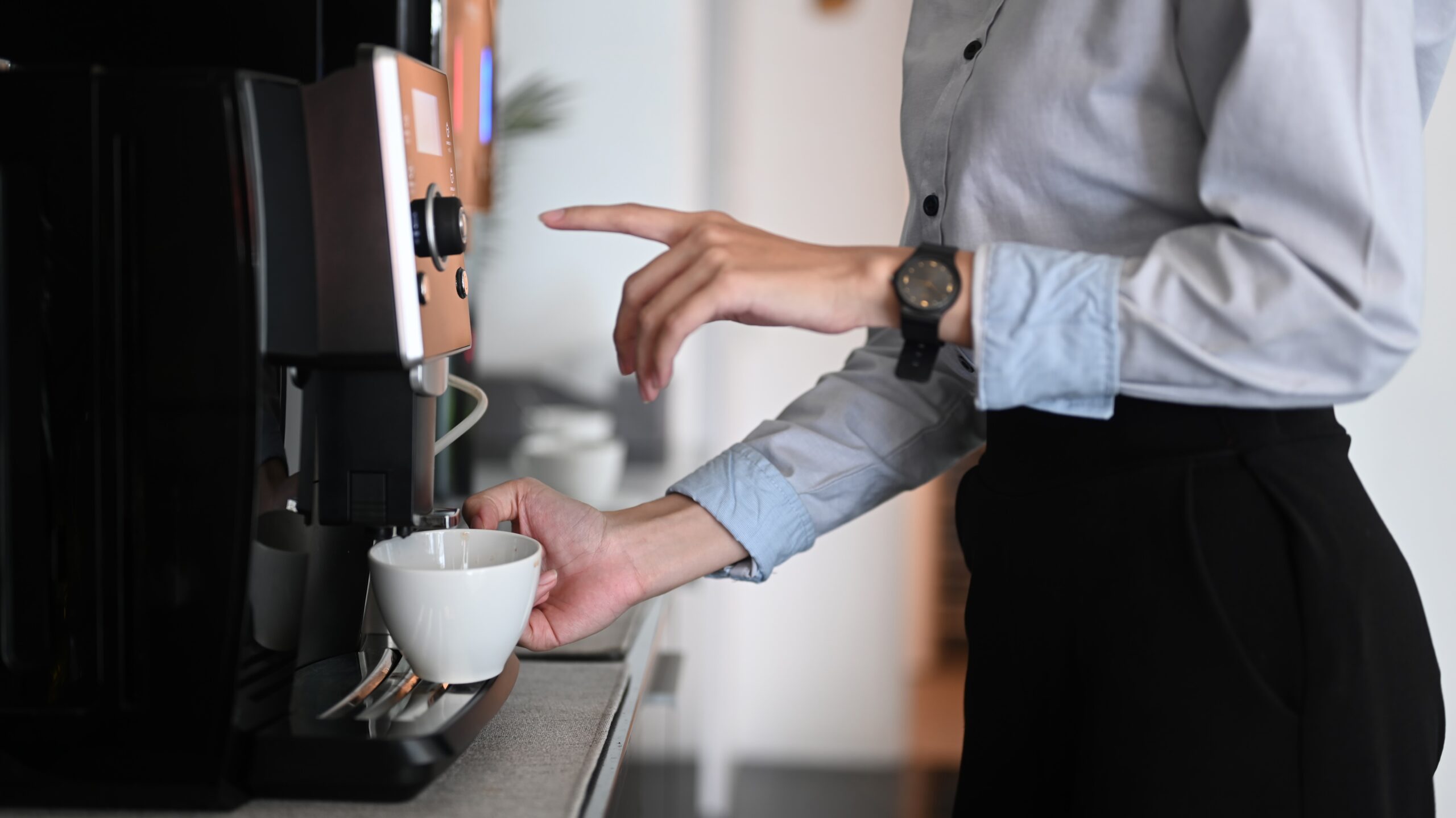 An office worker in a shirt selecting a drink from a commercial coffee machine