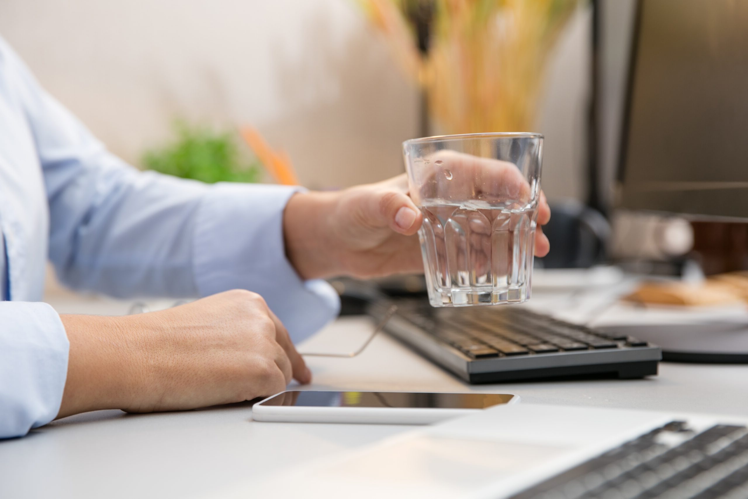 A man holding a glass of water while looking at a mobile phone