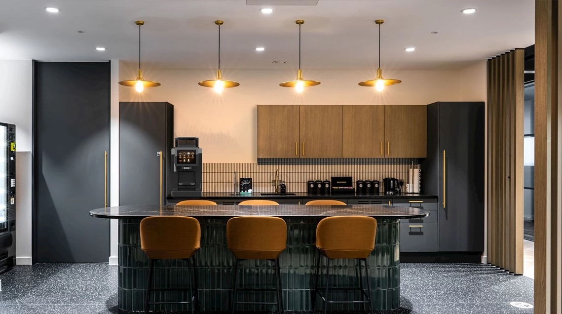 A dark office setup featuring black and orange colours with a Franke commercial coffee machine