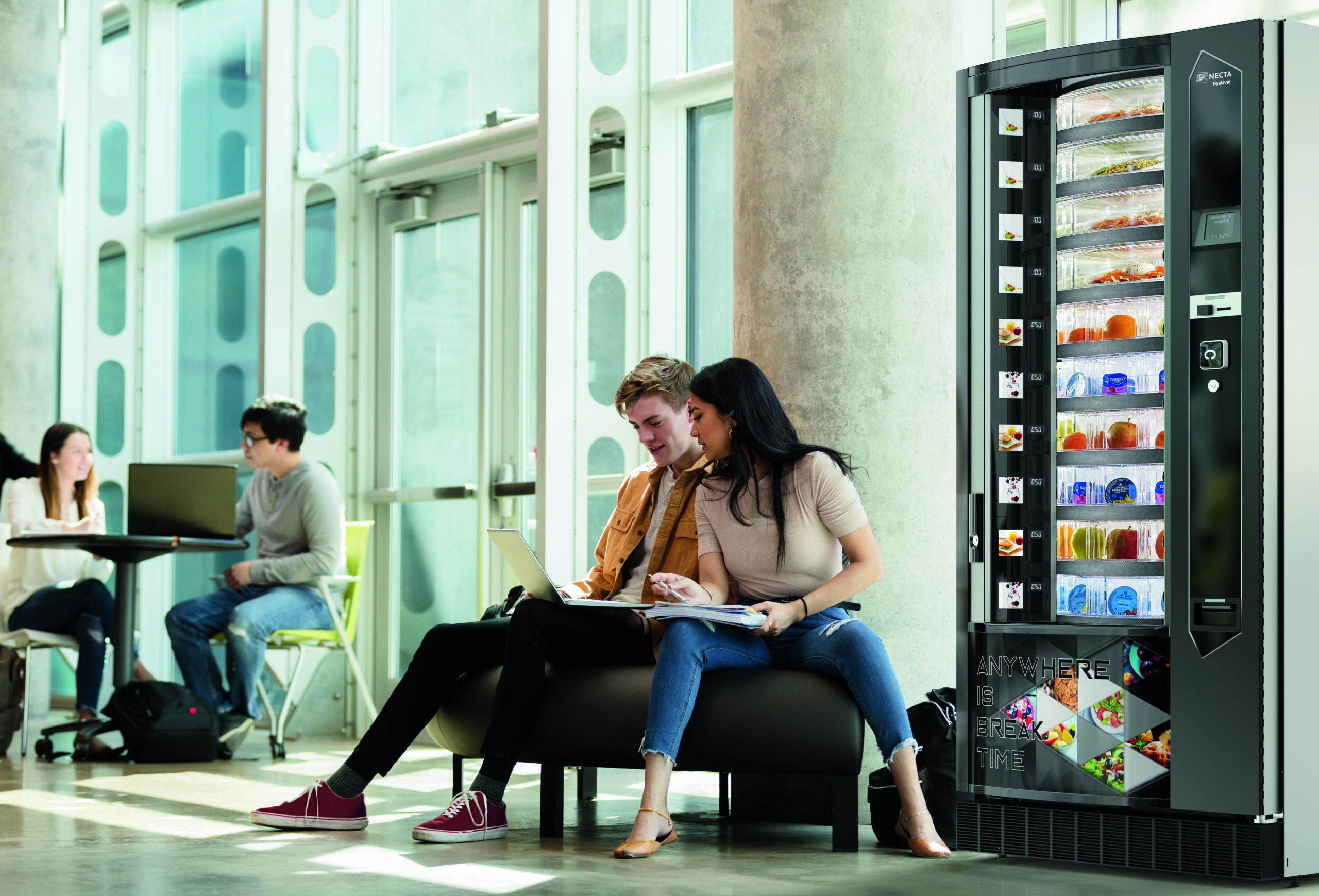 A diverse college couple study together for an exam in a campus lobby. They are looking at something on a laptop.