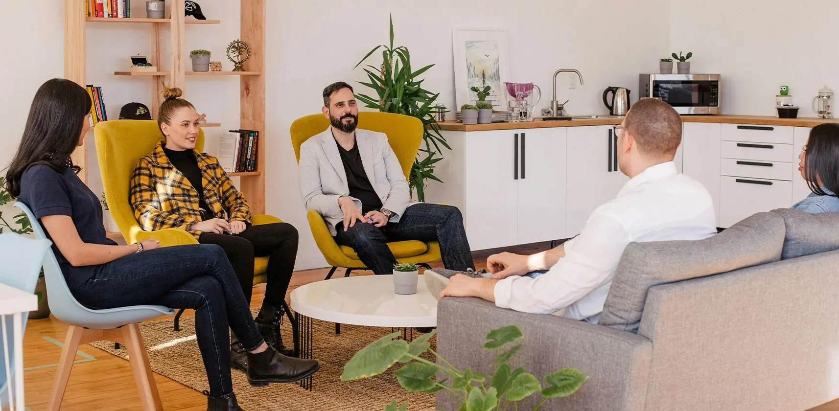 A group of students sat around a table on chairs talking