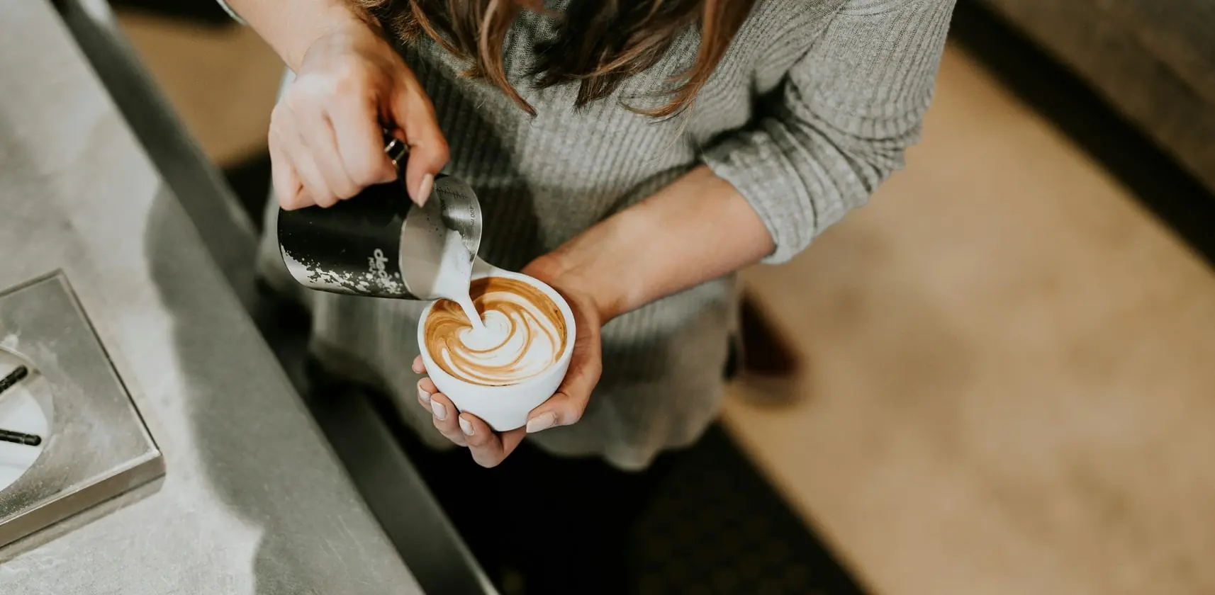 A barista creating latte art in a coffee cup for a hotel and hospitality guest