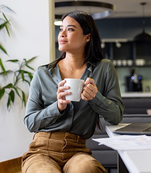 Thoughtful Latin American businesswoman taking a break and drinking a cup of coffee at the office