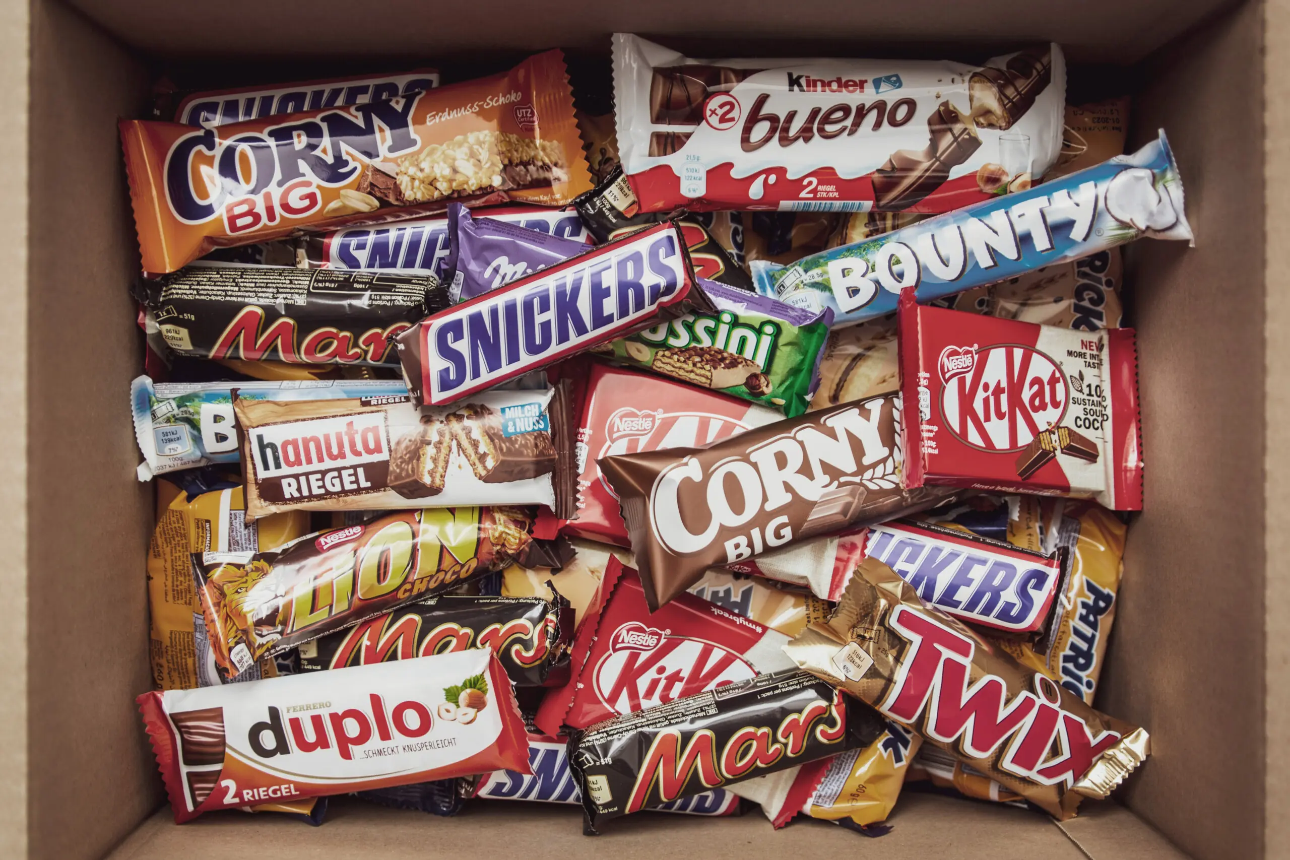 A selection of vending machine snacks in a box including Kitkat bars, snickers and Mars bars